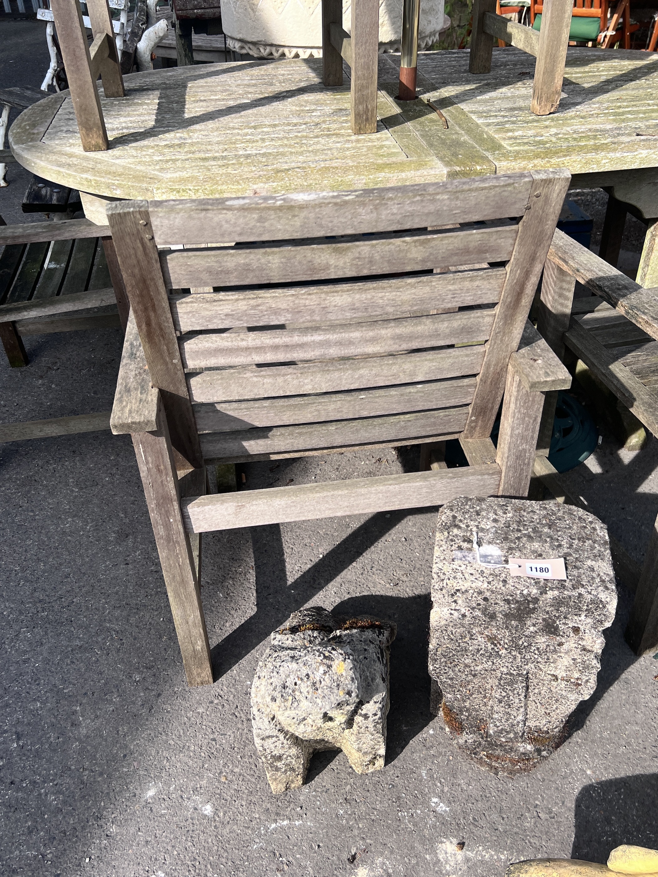 A weathered teak extending garden table, length 180cm, depth 110cm, height 76cm, together with six teak garden elbow chairs and a green canvas parasol